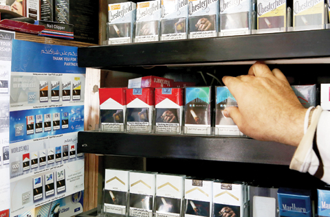KUWAIT: Packs of cigarettes and a poster announcing a hike in prices (left) are seen at a supermarket yesterday. - Photo by Yasser Al-Zayyat