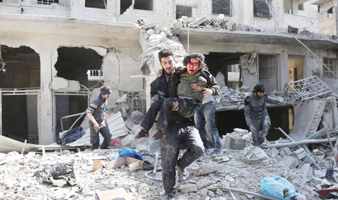     HAMOURIA, Syria: Syrians rescue a child following a regime air strike in this rebel-held town in the besieged Eastern Ghouta region on the outskirts of the capital Damascus yesterday. - AFP 