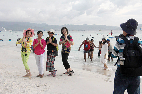 MALAY, the Philippines: Tourists pose for photos along a beach on Boracay island in Malay town, Aklan province, central Philippines. —AFP