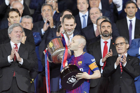 MADRID: Spain’s king Felipe VI looks at Barcelona’s Spanish midfielder Andres Iniesta kissing the trophy after the Spanish Copa del Rey (King’s Cup) final football match Sevilla FC against FC Barcelona at the Wanda Metropolitano stadium in Madrid. Barcelona won 5-0. — AFP