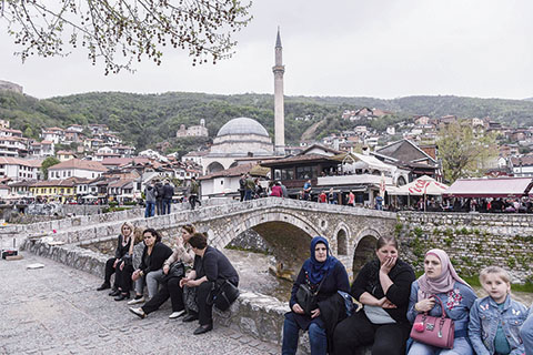 People sit next to the stone bridge overlooking the town of Prizren on April 15, 2018.nThe Ottomans controlled the Balkans from the 14th to the 19th century. They drew top public servants and leaders from the volatile region to help run an empire which stretched up to modern-day Austria and Hungary, and across North Africa and the Middle East. On May 20, 2018, Erdogan holds a rally in the Bosnian capital Sarajevo to drum up support among the Turkish diaspora for the snap elections he called for June 24. / AFP PHOTO / ARMEND NIMANI