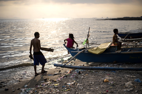 MANILA: Children sit on a wooden boat in Manila Bay.—AFP
