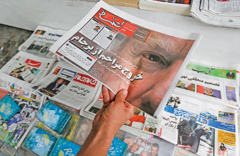 TEHRAN: An Iranian displays the front page of a newspaper in Tehran yesterday a day after US President Donald Trump (portrait) announced the US is pulling out of the nuclear deal. — AFP