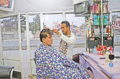 In this photograph taken on June 8, 2018, an Afghan barber cuts hair of his customer in his barbershop in Mazar-i-sharif. / AFP PHOTO / FARSHAD USYAN