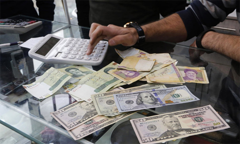 Iranians trade money at an exchange in Tehran. Iran took drastic measures last month to stem the decline in the free market rate, arresting foreign exchange dealers, freezing speculators’ accounts and raising interest rates. (AFP)