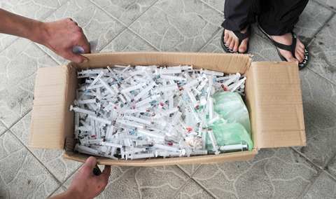 KIEV: (FILES) In this file photograph a social worker collects a box of used syringes at an needle exchange spot at an HIV/AIDS clinic in Kiev.-AFPn
