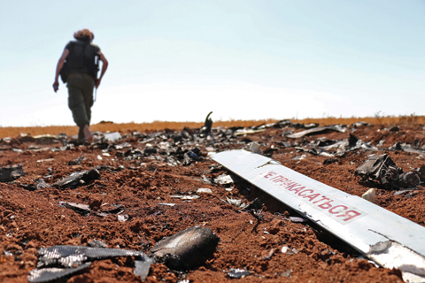 BARQAH, Syria: A rebel fighter walks near the remains of a Syrian regime drone that was shot down by Israel the day before, in a field near Barqah, a few dozen kilometers from the Israeli-occupied Golan Heights. — AFP