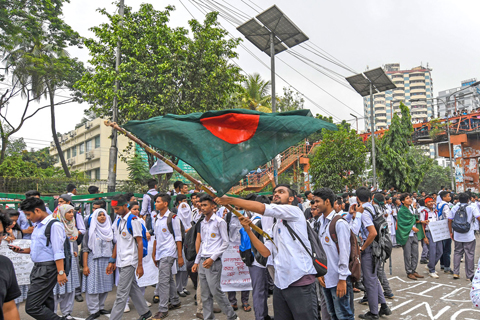 DHAKA: A Bangladeshi student wave Bangladesh’s national flag as they block a road during a student protest yesterday following the deaths of two college students in a road accident . — AFP