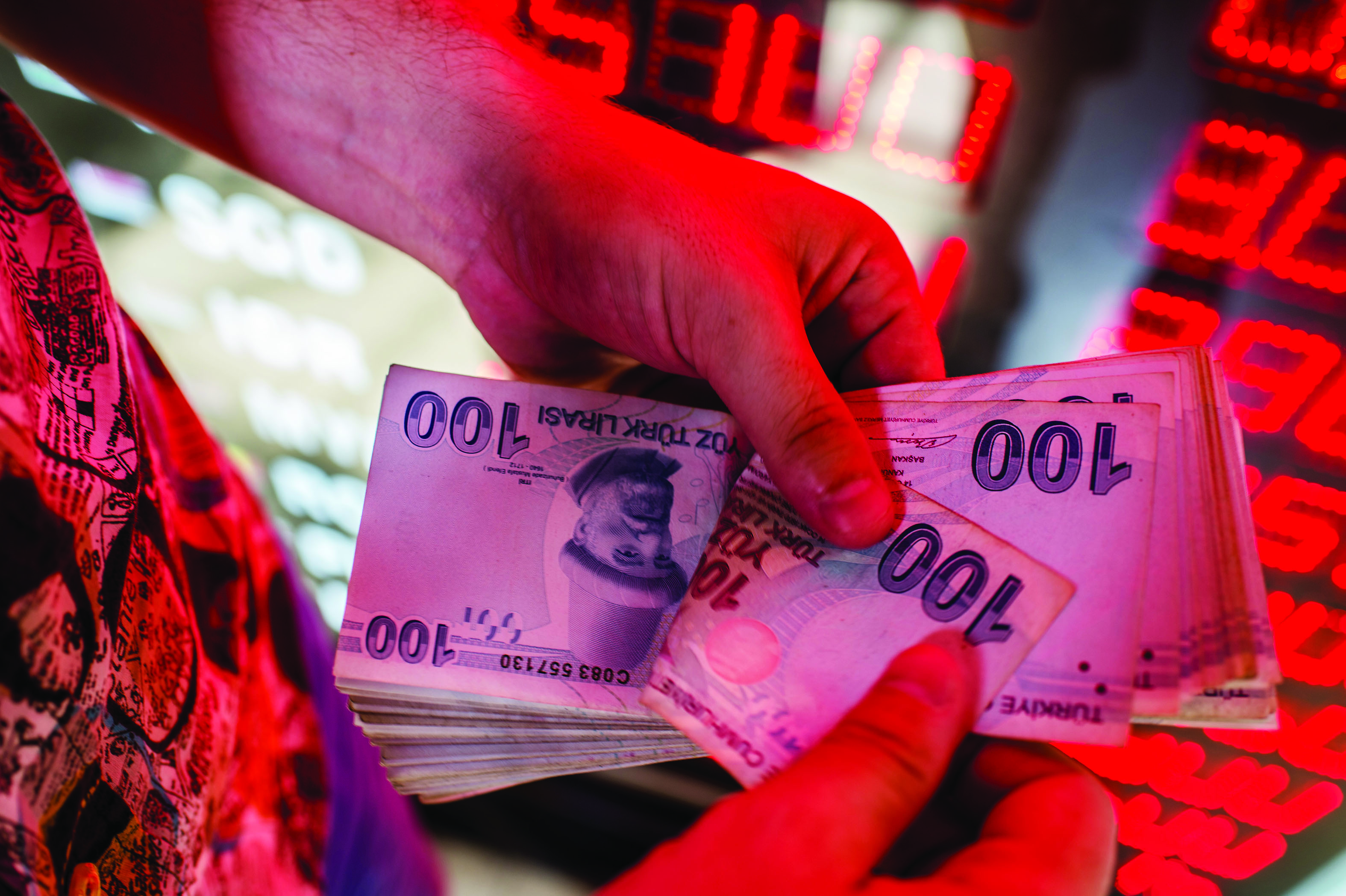 ISTANBUL: A money changer counts Turkish lira banknotes at a currency exchange office in Istanbul. - AFP