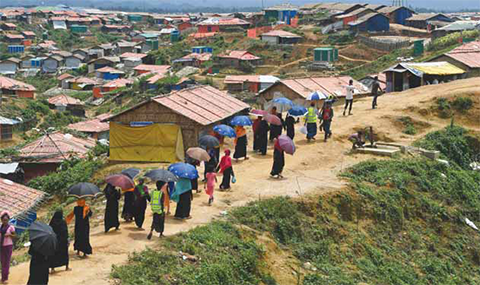 UKHIA: Rohingya refugee volunteers walk along Balukhali refugee camp in Ukhia district near Cox’s Bazar. — AFP