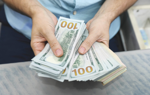 ANKARA: A man counts dollar bills in a money exchange office in Ankara. The lira has fallen 42 percent against the dollar this year. — AFP