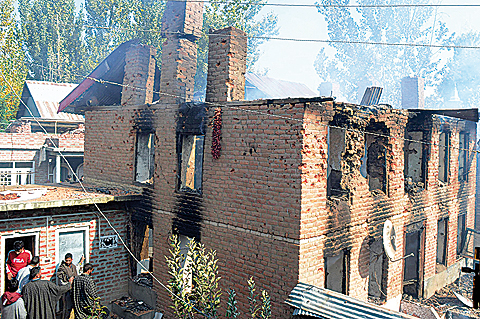 KASHMIR: Indian Kashmiri residents look on as smoke billows from a house after a gunfight with Indian government forces in Kulgam town, some 65 kms south of Srinagar yesterday. – AFP nn