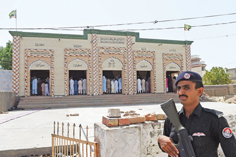 Pakistani policeman stands guard as Muslims offer Friday prayers in Mithi