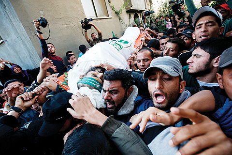 GAZA: Mourners carry the body of Nour Baraka, one of seven Palestinians killed during an Israeli special forces operation in the Gaza Strip, during his funeral yesterday in Khan Younis. - AFP 
