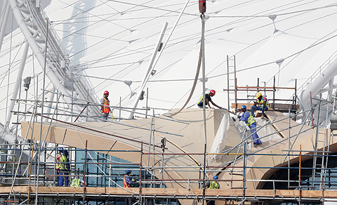 DOHA: Workers are pictured on scaffolding at the Khalifa International Stadium. — AFP