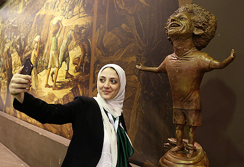 SHARM EL SHEIKH: A woman takes a selfie by a statue of Liverpool's Egyptian forward Mohamed Salah displayed at the World Youth Forum in Sharm El Sheikh, on November 5, 2018. - AFPn