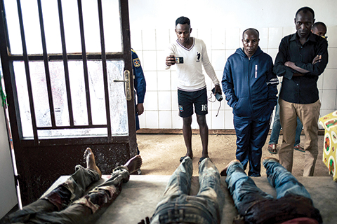 EDITORS NOTE: Graphic content / People in the morgue of Beni hospital look at the bodies of the civilians killed in an attack in Masiani district in Beni last night by armed men, on December 23, 2018. - At least five people, including four civilians, were killed in an attack by suspected Ugandan rebels in DR Congo, an AFP correspondent and witnesses said on December 23, 2018. The attack targeted the locality of Masiani in the Beni region of eastern Democratic Republic of Congo overnight. (Photo by ALEXIS HUGUET / AFP)