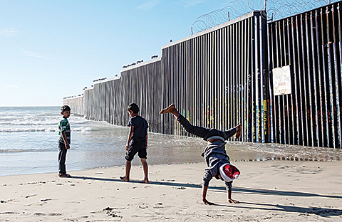 Children travelling with the Central American migrants that hope to reach the United States, play at the beach next to the US-Mexico border fence in Playas de Tijuana, Baja California State, Mexico, on December 29, 2018. - El Salvador insisted Saturday that it is taking steps to curb illegal migration to the United States, fending off criticism from President Donald Trump, a day after he threatened to cut off aid to nations in Central America's Northern Triangle -- Honduras, Guatemala and El Salvador. (Photo by GUILLERMO ARIAS / AFP)