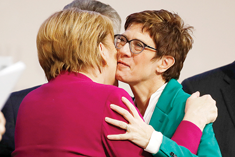German Chancellor Angela Merkel (L) bids farewell to her successor, newly-elected leader of the Germany's conservative Christian Democratic Union (CDU) party Annegret Kramp-Karrenbauer at the end of the CDU congress on December 8, 2018 at a fair hall in Hamburg, northern Germany. (Photo by Odd ANDERSEN / AFP)