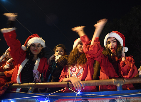 Girls wearing Santa Klaus costumes wave from a bus on a street in Karachi on December 21, 2018, as part of the Christmas celebrations. (Photo by ASIF HASSAN / AFP)