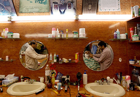 A Kuwaiti man who is having his beard shaved is reflected in a mirror at a market barber shop in Kuwait City on January 31, 2012. Kuwaits will head to polling stations on February 2 to choose among candidates contesting in a general election amid calls for sweeping reforms including a new constitution that would turn the oil-rich Gulf state into a full democracy.                    AFP PHOTO/MARWAN NAAMANI
