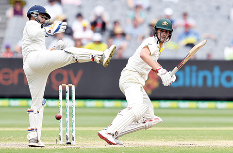 Australia's batsman Pat Cummins (R) plays a shot as India's wicketkeeper Rishabh Pant looks on during day four of the third cricket Test match between Australia and India in Melbourne on December 29, 2018. (Photo by WILLIAM WEST / AFP) / -- IMAGE RESTRICTED TO EDITORIAL USE - STRICTLY NO COMMERCIAL USE --