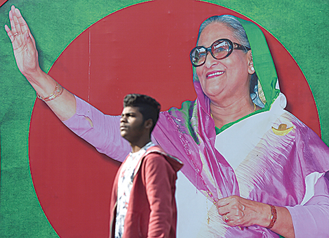 A Bangladeshi man walks past a photo of Prime Minister Sheikh Hasina, in Dhaka on December 29, 2018. - Bangladesh stepped up security on December 29 in a bid to contain violence during a general election expected to see Prime Minister Sheikh Hasina win a record fourth term. (Photo by Indranil MUKHERJEE / AFP)