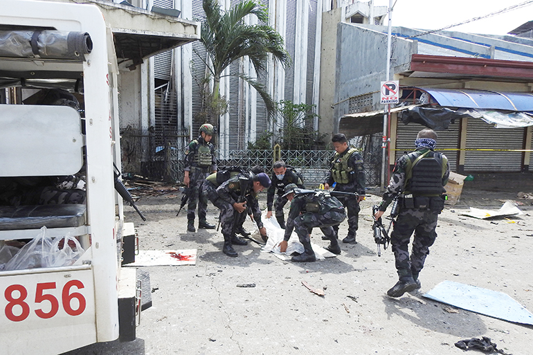 Philippine security personnel carry a body bag containing the remains of a blast victim after two bombs exploded at a church in Jolo, Sulu province on the southern island of Mindanao, on January 27, 2019. - At least 18 people were killed when two bombs hit a church on a southern Philippine island that is a stronghold of Islamist militants, the military said on January 27, days after voters backed the creation of a new Muslim autonomous region. (Photo by NICKEE BUTLANGAN / AFP)