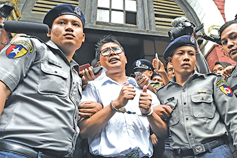 (FILES) This file photo taken on September 03, 2018 shows Myanmar journalist Wa Lone (C) is escorted by police after being sentenced by a court to jail in Yangon. - Two Reuters journalists jailed in Myanmar over their investigation of atrocities committed against the Rohingya will learn January 11 if an appeal against their conviction has succeeded. (Photo by Ye Aung THU / AFP)