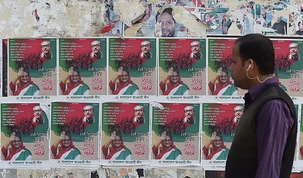 A Bangladeshi man walks past posters of Prime Minister Sheikh Hasina and her father Sheikh Mujibur Rahman, the founding father of Bangladesh, in Dhaka on December 29, 2018. (AFP)