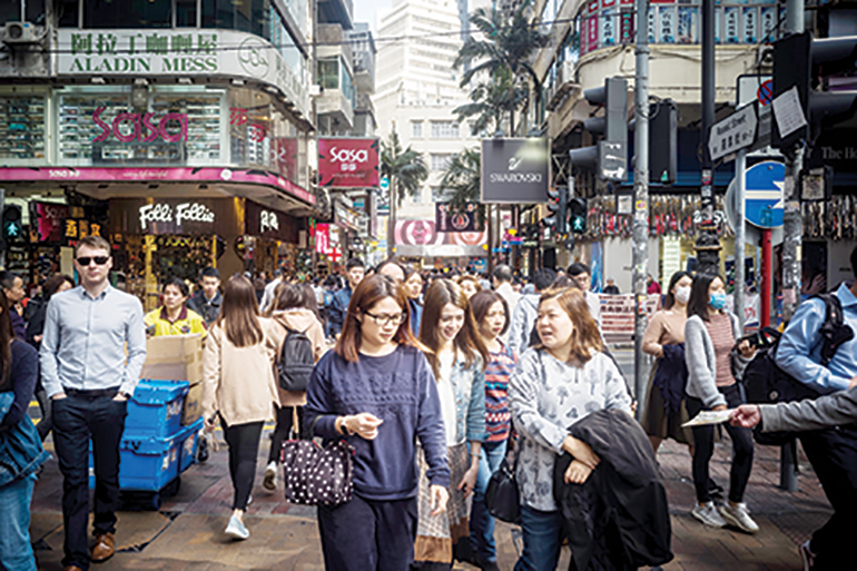 Pedestrians walk on a pavement along Russell Street in the shopping district of Causeway Bay in Hong Kong on January 11, 2019. - Russell Street replaced New Yorkís Upper Fifth Avenue as the worldís most expensive retail street by rental value, according to property consultants Cushman &amp; Wakefield in November last year. (Photo by Anthony WALLACE / AFP)