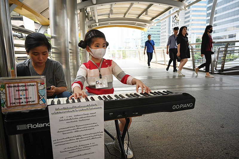 BANGKOK: A young girl wears a face masks as she plays a piano in the central business district. — AFP