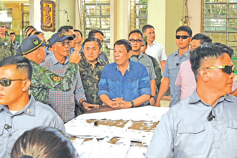 JOLO: Philippine President Rodrigo Duterte (C) and Defense Secretary Delfin Lorenzana (2nd L, with spectacles) listen to national police chief Director General Oscar Albayalde (L, in camouflage) as they inspect the damage area of a catholic cathedral. — AFP