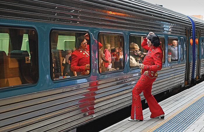 An Elvis fan uses the train window as a mirror at Central station before boarding a train to The Parkes Elvis Festival, in Sydney yesterday. — AFP photos