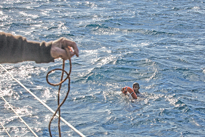A crew member from the Dutch-flagged Sea-Watch 3 rescue vessel throws a buoy and a rope to rescue a migrant, after he dived on January 4, 2019 from the vessel in the cold Mediterranean off Malta’s coast, in a attempt to reach the shore by swimming. — AFP