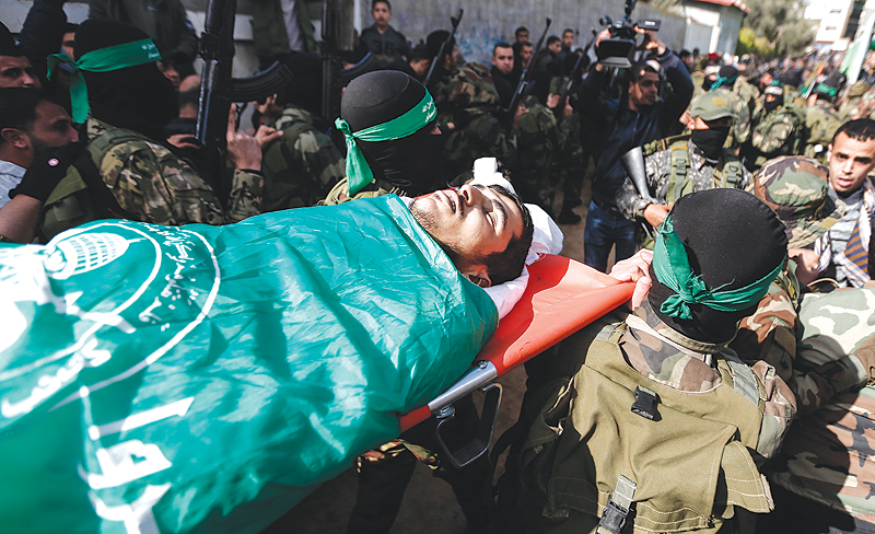 Masked Hamas gunmen carry the body of Mahmoud Al-Nabahin, 24, during his funeral in the Bureij refugee camp, in the central Gaza Strip. — AFP