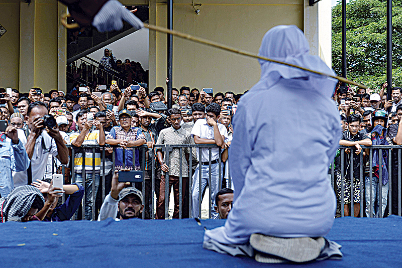 BANDA ACEH: An 18-year-old Indonesian woman is caned in public yesterday as punishment for being caught cuddling with her boyfriend. —AFP