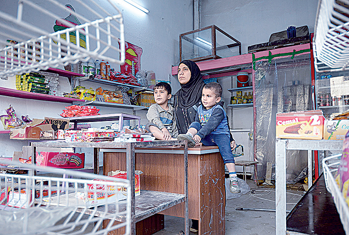 MOSUL: Umm Mustafa, a 27-year-old widow, rests with her sons in her grocery shop in Iraq’s northern city of Mosul.—AFP