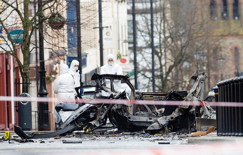 DERRY: Police forensic officers inspect the aftermath of a suspected car bomb explosion. —AFP