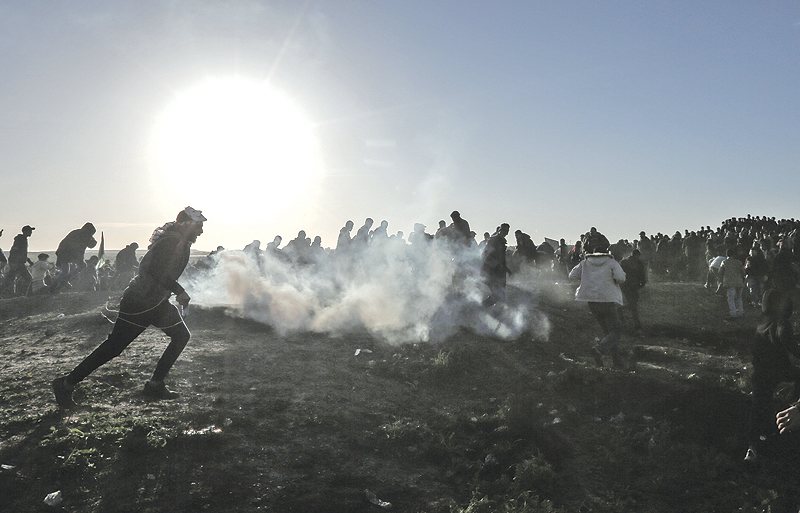 Palestinian protesters run through tear gas fumes during clashes with Israeli forces following a demonstration along the border with Israel east of Gaza City. — AFP