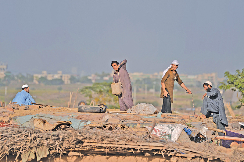 ISLAMABAD: In this picture Afghan refugees make a roof for a mud house at a refugee camp on the outskirts of Islamabad. — AFP