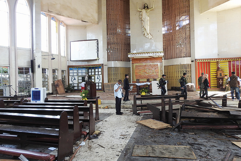 JOLO: Philippine soldiers walk past the damaged area of a catholic cathedral in Jolo town, sulu province, in southern island of Mindanao yesterday a day after two explosions tore through the cathedral. — AFP