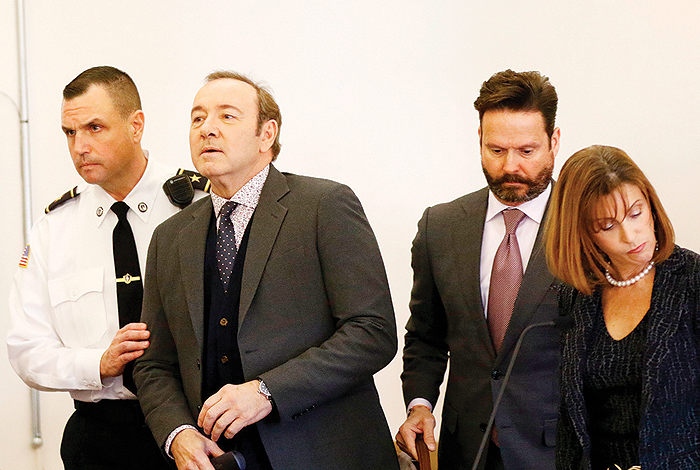 NANTUCKET: Kevin Spacey is escorted by a court officer during his arraignment at the Nantucket District Court yesterday. — AFP