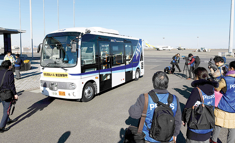 TOKYO: Journalists look at a driverless bus during an open test drive demonstration atnTokyo’s Haneda International Airport yesterday. — AFP