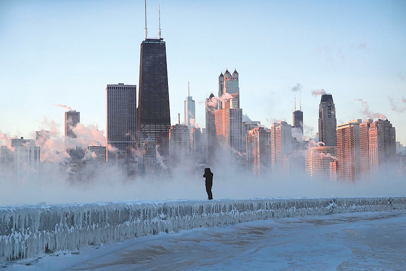 CHICAGO: A man walks along an ice-covered break-wall along Lake Michigan yesterday. — AFP