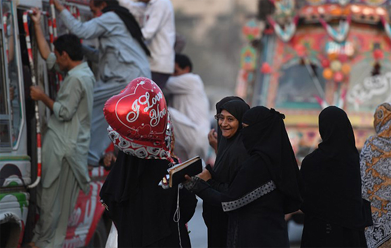 A Pakistani woman holds heart-shape balloon at a street on Valentine's Day in Karachi on February 14, 2018 AFP