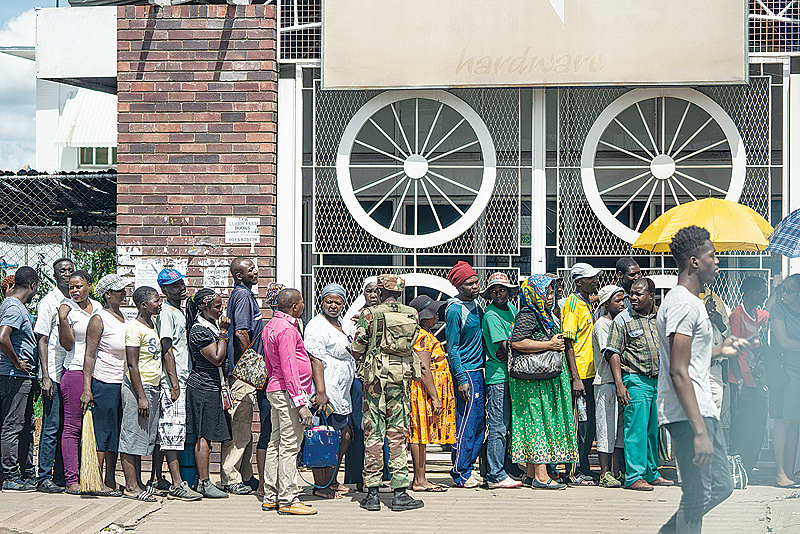 BULAWAYO: A Zimbabwean soldier watches shoppers lining up, in Bulawayo on January 17, 2019 as order is slowly restoring. —AFP