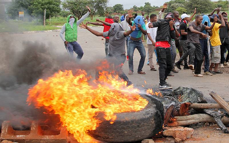 Protesters stand behind a burning barricade during protests on a road leading to Harare, Zimbabwe, on January 15, 2019. [Photo, Reuters]