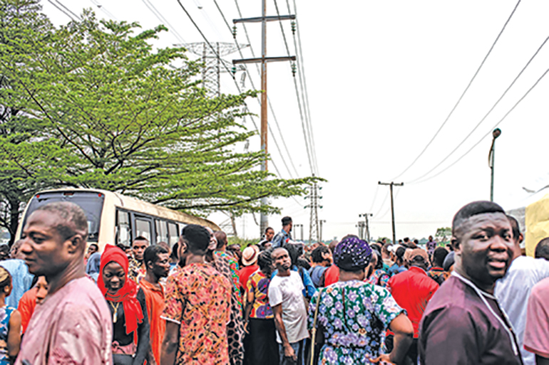 A crowd at one of the Permanent Voter Cards (PVCs) collection points listens attentively for names to be called out over a megaphone to receive their voting card in Lagos on February 8, 2019. - Would be voters had until February 8 to collect their Permanent Voter Cards (PVCs) but due to an out cry about not receiving their cards and logistical difficulties at collection points the Independent National Electoral Commission (INEC) has extended the collection date to February 11. (Photo by STEFAN HEUNIS / AFP)