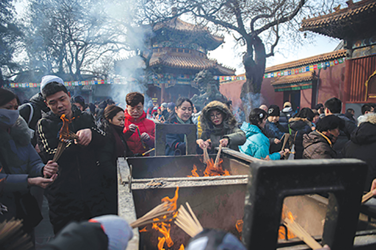 People burn incense as they pray for good fortune at the Yonghegong, or Lama Temple in Beijing on the fifth day of the Lunar New Year on February 9, 2019. - Chinese communities around the world welcomed the Year of the Pig on February 5, ushering in the Lunar New Year with prayers, family feasts and shopping sprees. (Photo by NICOLAS ASFOURI / AFP)